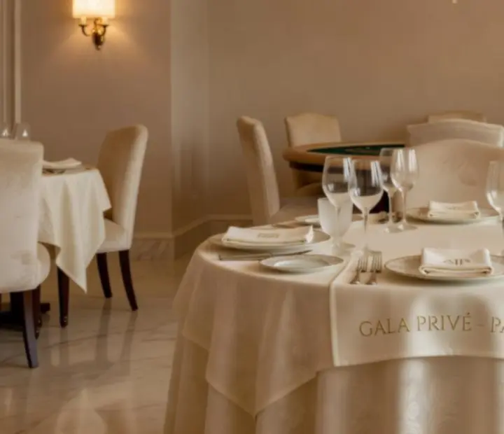 Table de gala éclairée à la bougie avec jetons ludiques et cartes devant une salle de restaurant gastronomique